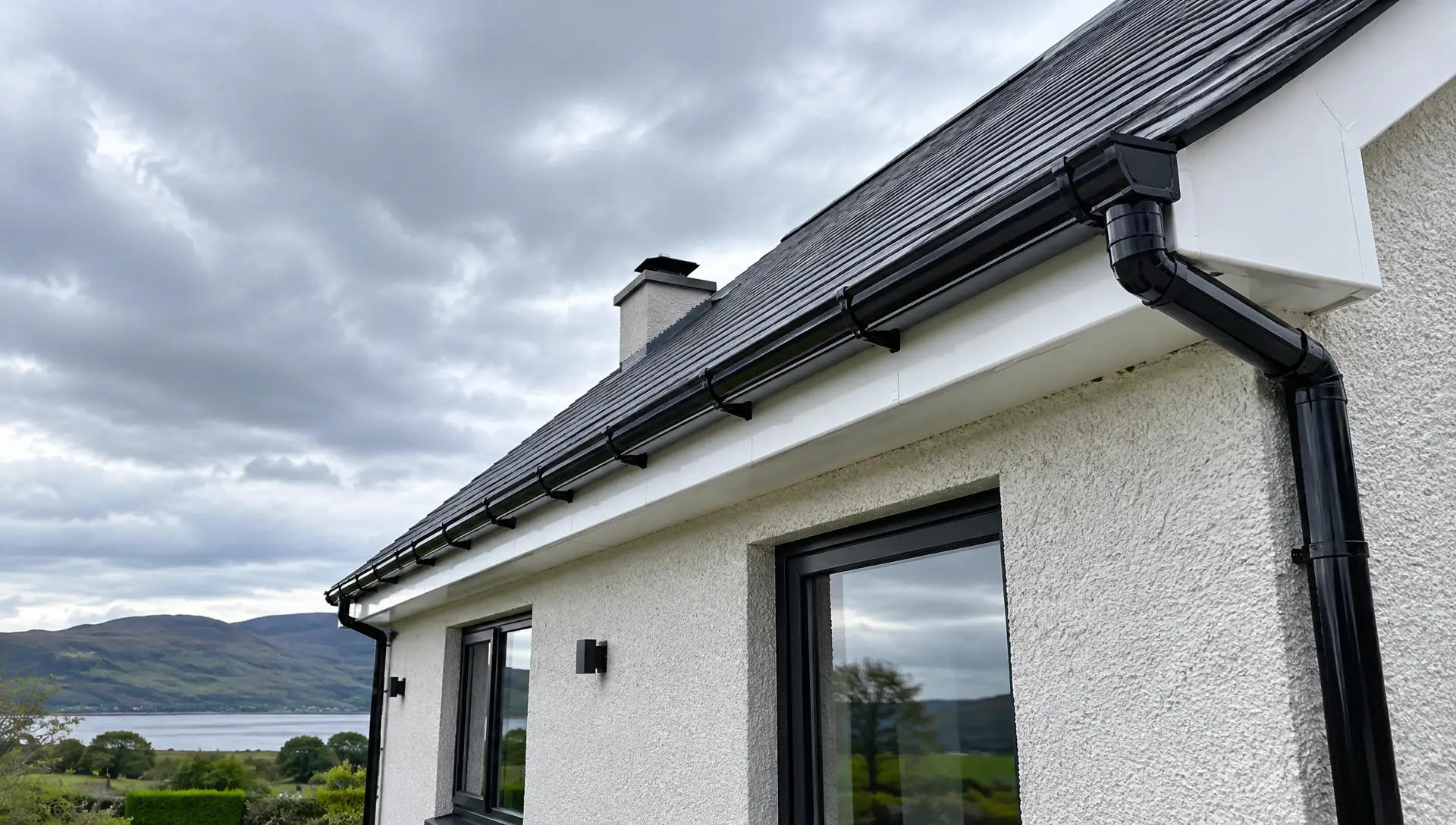 Black uPVC guttering and white fascia along the slate roof of an Irish-style house