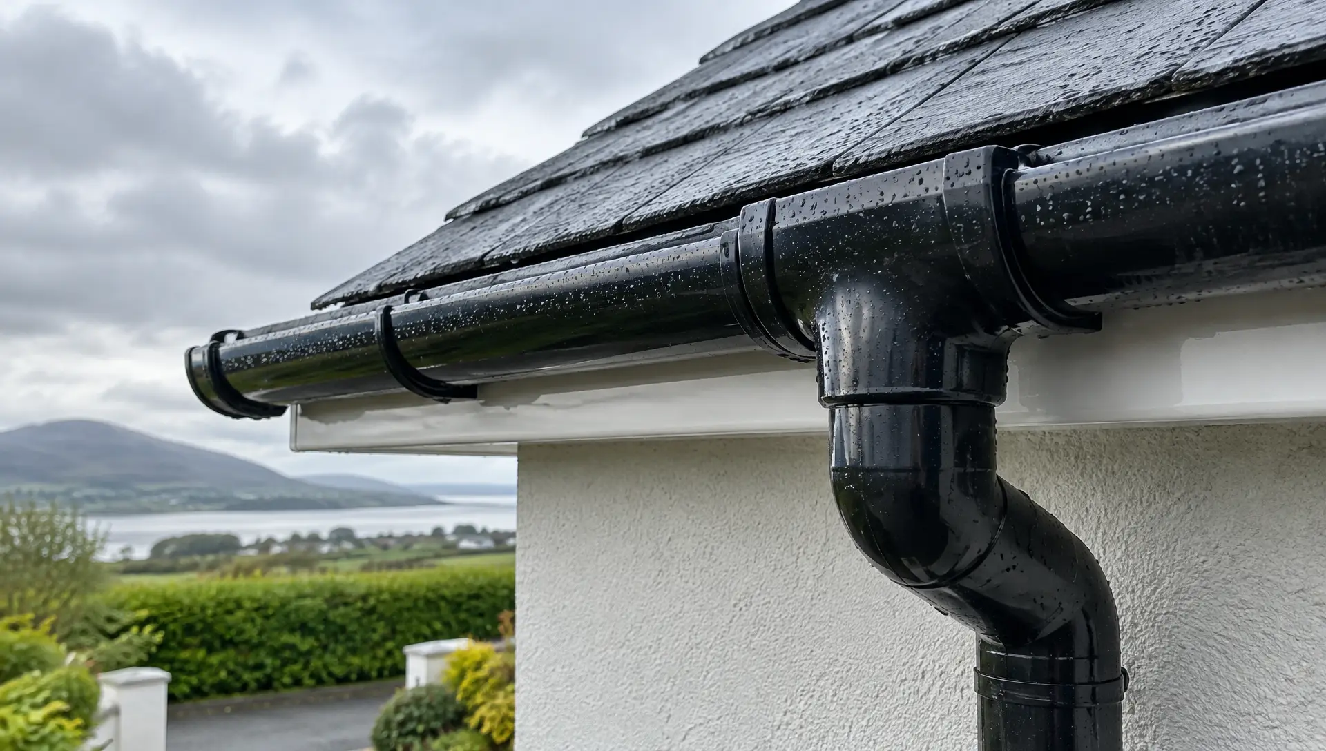 Close-up of a black uPVC gutter joint and downpipe outlet after rain